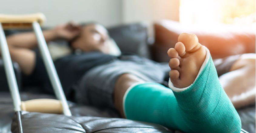 Pojištění pracovní neschopnosti: muž se zraněnou nohou ležící na posteli.