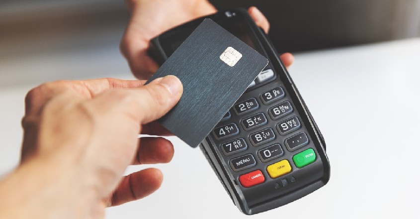 Člověk platící bezkontaktně platební kartou bez zadávání PIN kódu.