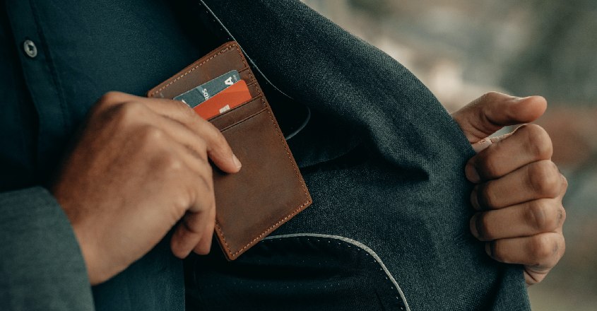 Muž schovává peněženku s kreditními kartami do kapsy kabátu.