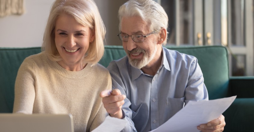 Veselý pár seniorů si prohlíží nabídku úvěrů pro důchodce