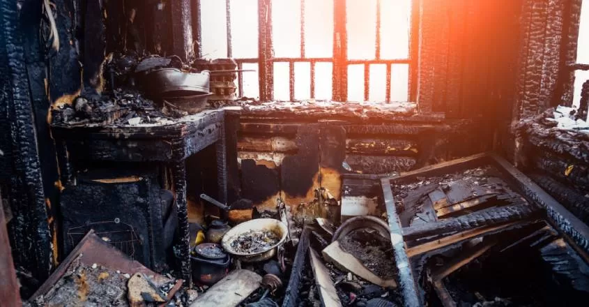 Vyhořelý byt se zničeným nábytkem a ohořenými stěnami.