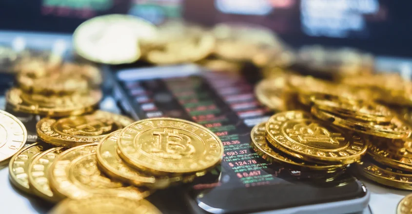 Bitcoinové mince položené na telefonu s grafy.