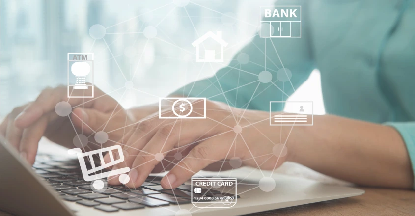 Klíčovým faktorem proti kybernetickým útoků je nejen ochrana bank, ale především ostražitost samotných klientů. Ruce píšící na notebooku s digitálními ikonami bankovnictví, plateb a online nákupů.